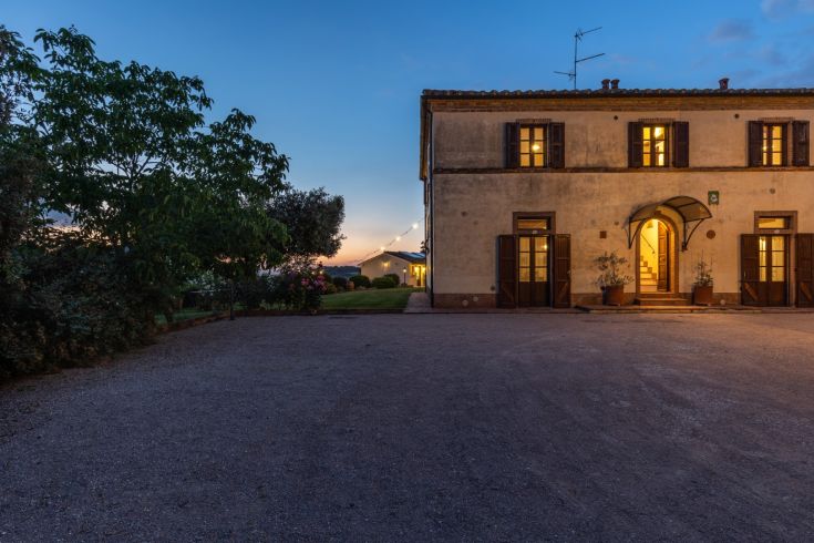 A historic farmhouse surrounded by the tranquility of the Umbrian countryside at dusk.