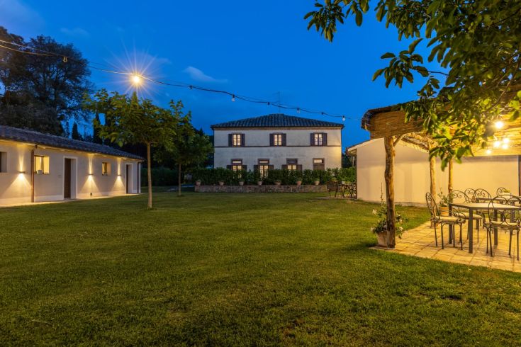 Farmhouse located in the Umbrian countryside, featuring a well-maintained garden and a peaceful evening atmosphere.