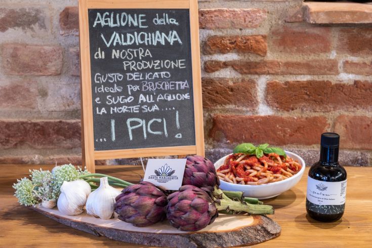 Traditional pici pasta with aglione sauce, garnished with fresh and fragrant ingredients.