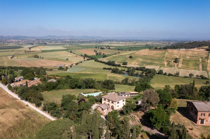A farmhouse located in the Umbrian countryside, surrounded by olive groves and green fields.