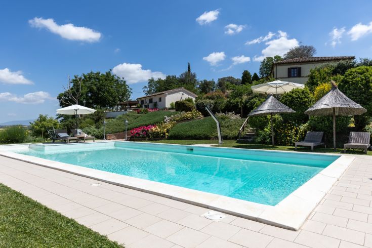 A pool located in a natural setting, surrounded by greenery and flowers.