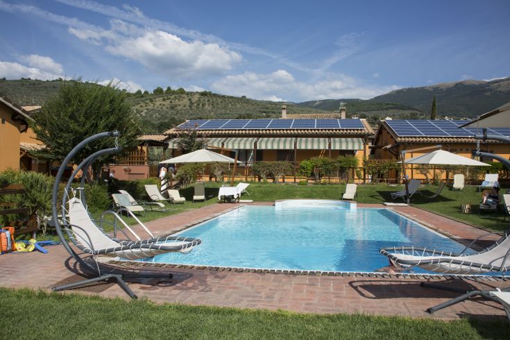 Une piscine située dans un environnement paisible, entourée d'arbres et de maisons. Un endroit pour se détendre.