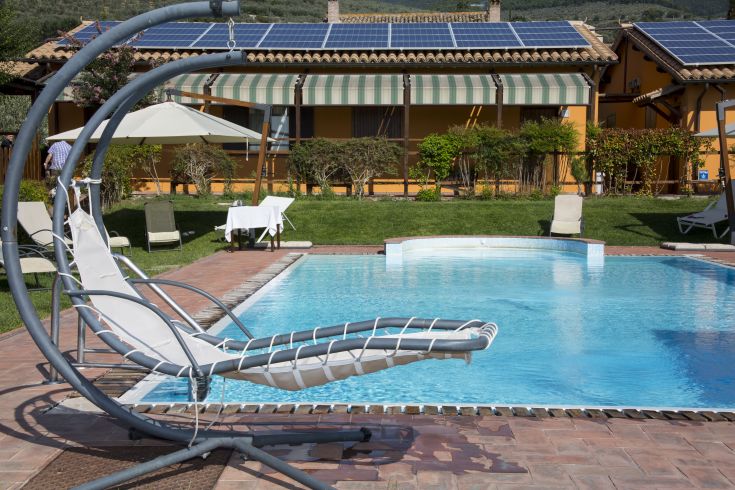 Piscine avec chaises longues au Borgo dell'Ulivo, entourée de collines verdoyantes.