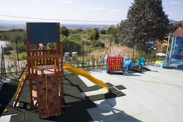 Une aire de jeux extérieure avec un toboggan coloré et des équipements dans un cadre naturel.