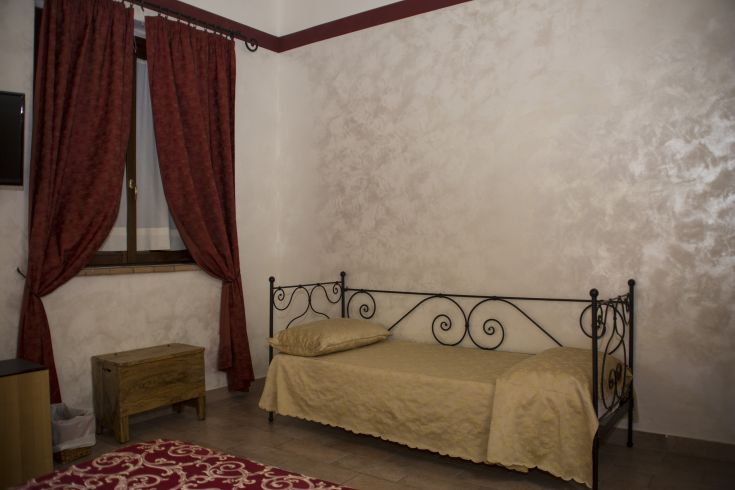 Chambre simple avec un lit simple et des rideaux rouges, idéale pour un séjour relaxant.