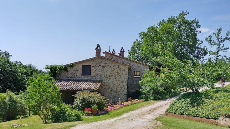Image of a farmhouse in greenery, featuring a well-maintained garden and a peaceful space for relaxation.