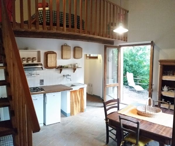 Cucina funzionale con zona pranzo, panorama su un giardino e accesso a un'area esterna.