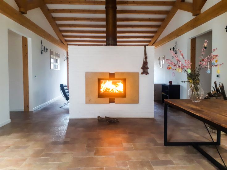 Gemütliche Umgebung mit einem zentralen Kamin, beleuchtet von einer einfachen Blumendekoration.