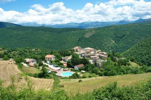 Scena di un tranquillo villaggio circondato da colline verdeggianti e natura, immerso in un'atmosfera serena.
