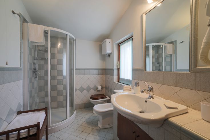 Une salle de bain moderne avec une décoration élégante, comprenant une douche, un lavabo et des accessoires essentiels. Éclairée par la lumière naturelle.