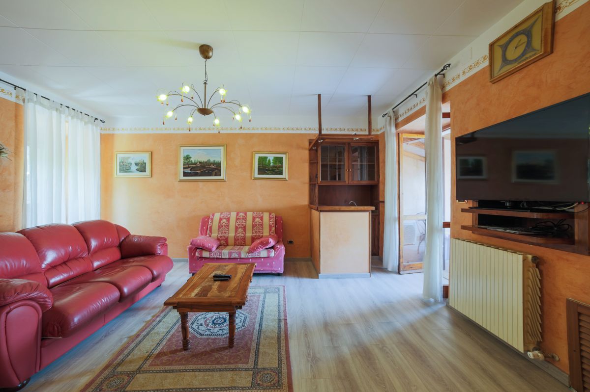 Ampio soggiorno con divani rossi e arredi in legno, perfetto per momenti di relax.