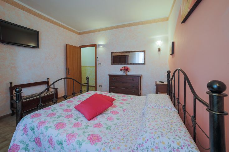 Une chambre simple avec un lit double et des décorations florales dans une ambiance calme.