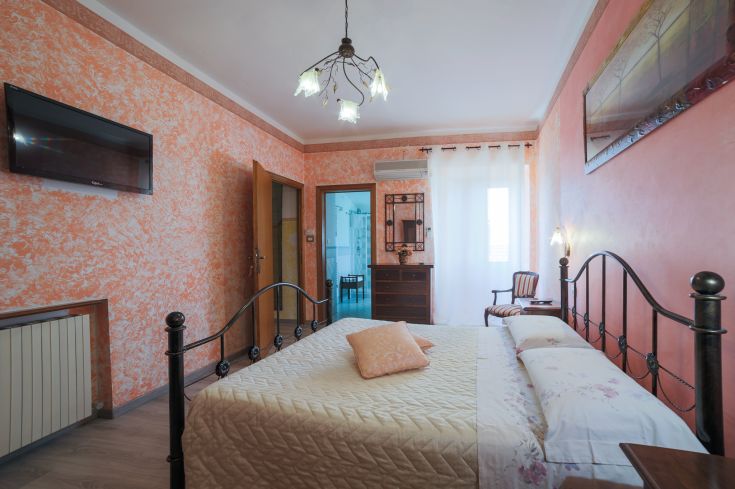 Chambre chaleureuse avec des murs orange et un grand lit, décor simple et accueillant.