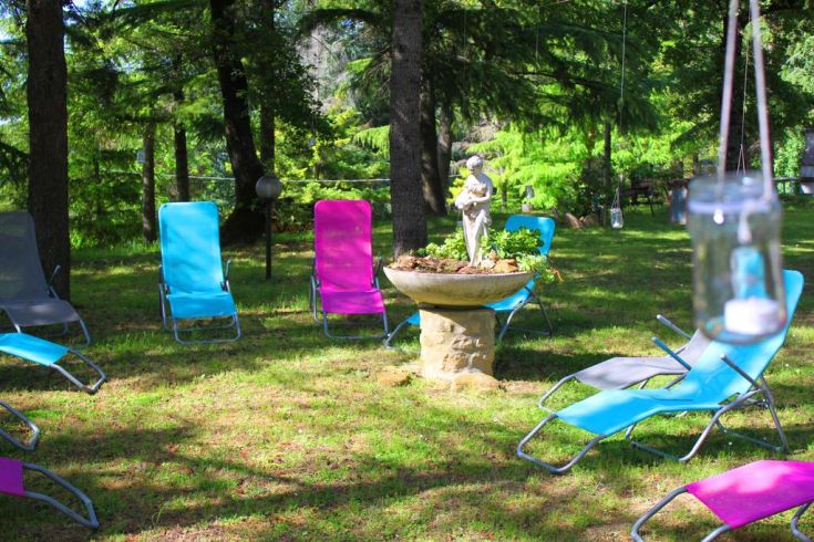 A bright garden with colorful loungers and a statue at the center, perfect for relaxation.