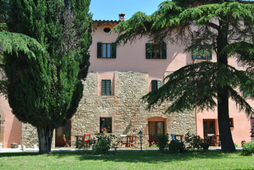 A 17th-century building nestled in a tranquil setting, surrounded by gardens and lush green spaces typical of Umbria.