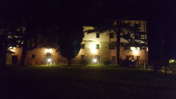 Edificio ben illuminato di notte, immerso nel verde tipico dell'Umbria.