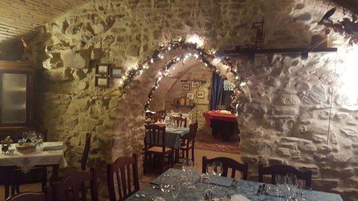Interno di un ristorante con archi in pietra e decorazioni semplici, dall'atmosfera calda e familiare.