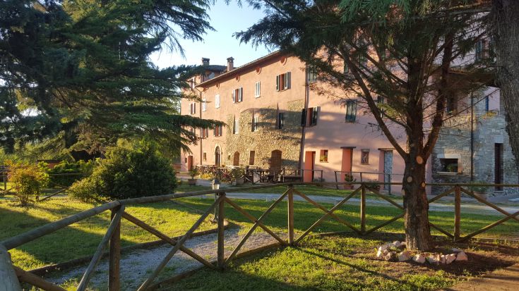 Scena di un tipico casale in campagna, circondato da un ampio verde, adatto per una breve vacanza tranquilla.