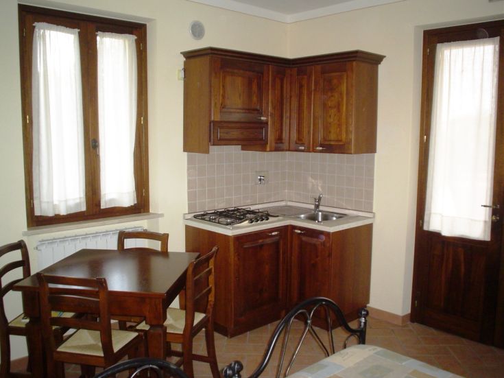 Cuisine en bois simple avec table et fenêtres laissant entrer la lumière naturelle. Idéale pour les repas en compagnie.