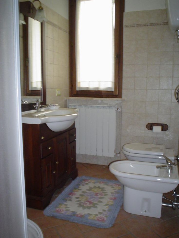 Salle de bain spacieuse et lumineuse, dotée de meubles en bois et de carreaux de couleurs claires.