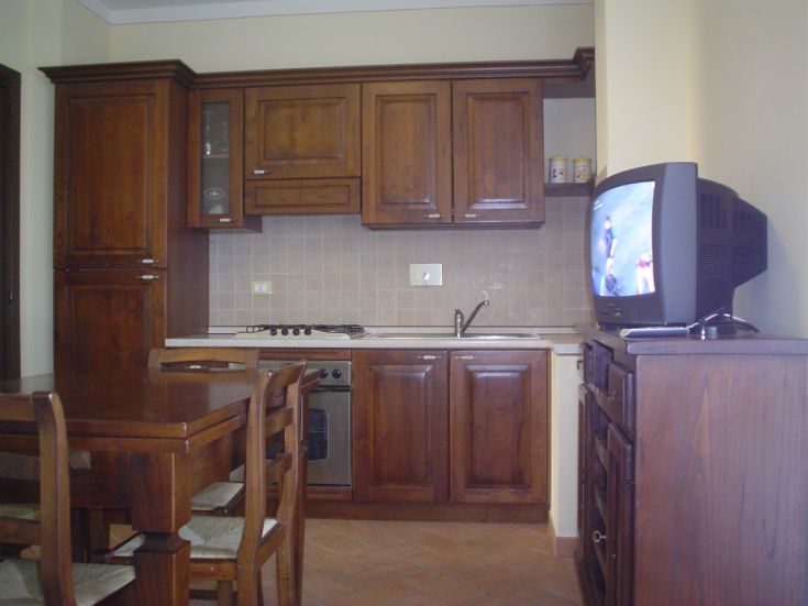 Cuisine confortable avec des meubles en bois et une télévision, parfaite pour une atmosphère familiale.