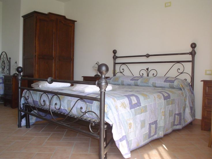 Chambre confortable avec des lits en fer et des décorations vives, parfaite pour un séjour paisible.