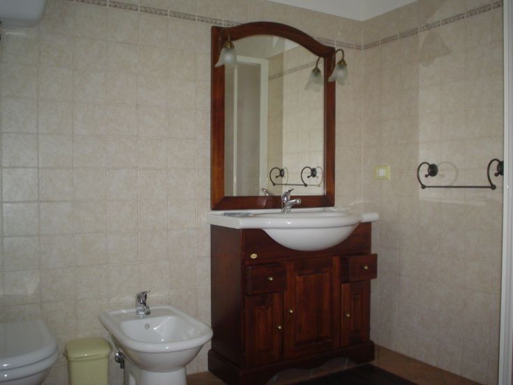 Une salle de bain avec des carreaux clairs, un lavabo traditionnel et un miroir, idéale pour des moments de détente.