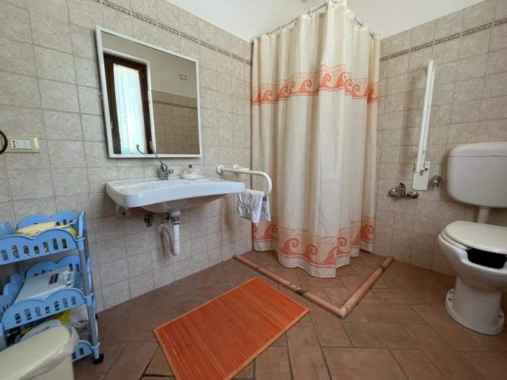 Intérieur d'une salle de bains moderne avec douche, lavabo et toilettes en bon état.