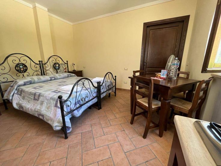 Intérieur d'un appartement spacieux avec des lits en fer et une table à manger, idéal pour un séjour confortable.