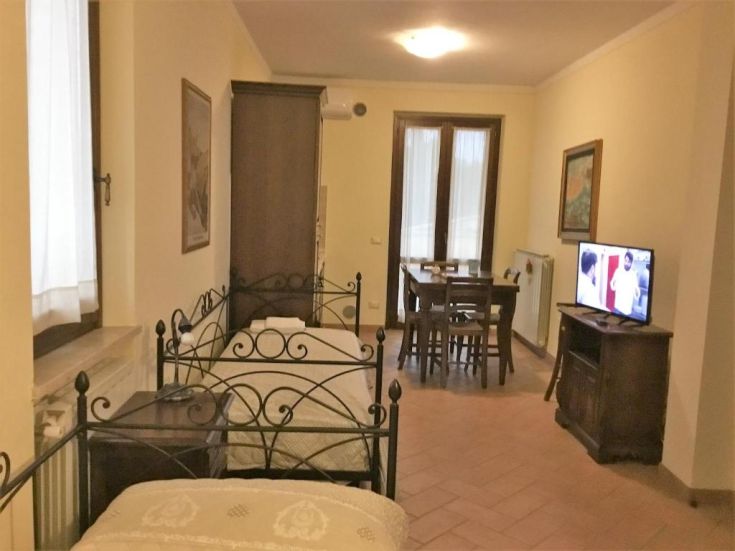 Intérieur d'un appartement avec des lits en fer forgé et un salon lumineux, idéal pour des moments de détente.