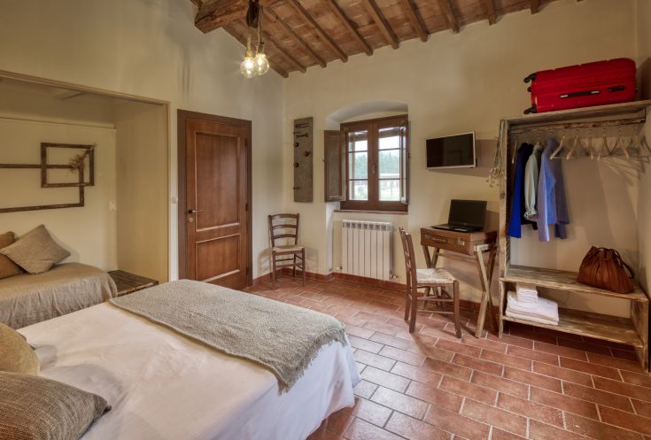 Camera semplice in agriturismo, dotata di comfort essenziali e affacciata su un ambiente naturale.