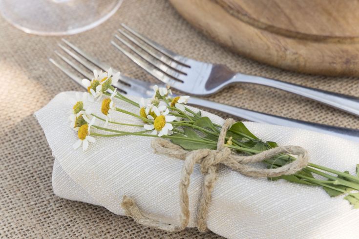 Fiori freschi adornano un tovagliolo in una semplice mise en place, adatta per un pranzo estivo.
