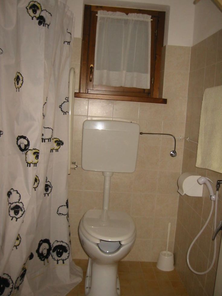 Ein funktionales und komfortables Badezimmer, dekoriert mit Schafmotiven, ausgestattet mit einem Fenster und den wichtigsten Annehmlichkeiten.