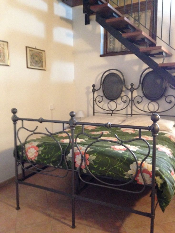 Gemütliches Zimmer mit einem Eisenbett und Blick von einer Treppe. Ideal für Entspannungsmomente.