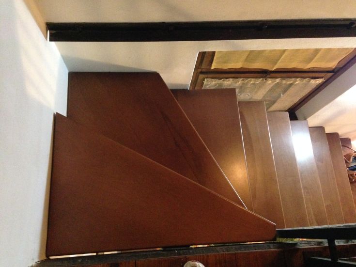 Eine einfache und schlichte Holztreppe, die zu den oberen Etagen führt, umgeben von einer warmen Atmosphäre.