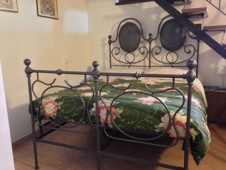 Gemütliches Schlafzimmer mit einem Schmiedeeisenbett und schlichten Dekorationen.