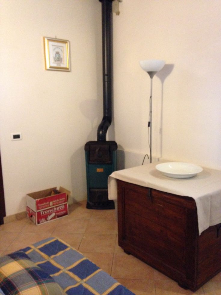 Eine gemütliche Ecke einer Wohnung mit einem Ofen und grundlegenden Möbeln.