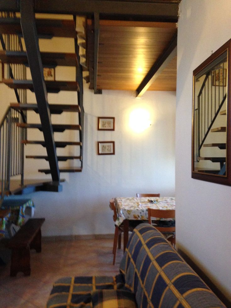 Ein schlichtes und funktionales Interieur mit einer Treppe aus Holz, einem Essbereich und einem bequemen Sofa.