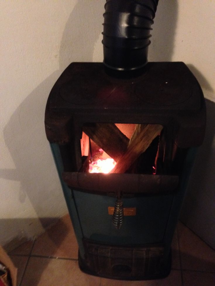 Holzofen in Betrieb mit Holzstücken darin, der Wärme abgibt und eine gemütliche Atmosphäre schafft.