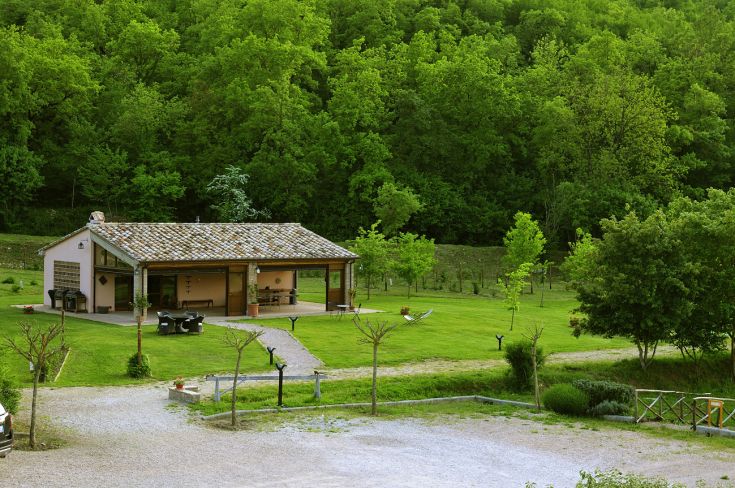 A peaceful farmhouse surrounded by greenery, featuring a pool, gardens, and relaxation areas.