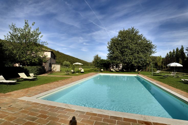 A pool located in a farmhouse, surrounded by meadows and trees, perfect for relaxation.