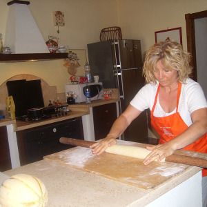 A woman is making pasta in a cozy, warm kitchen, creating a family-friendly atmosphere.