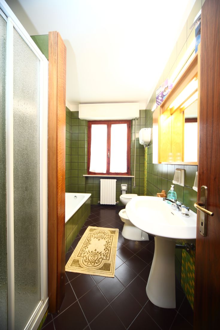 Heller Badezimmerbereich mit modernen Armaturen und hellgrünen Fliesen, ideal für entspannende Momente.
