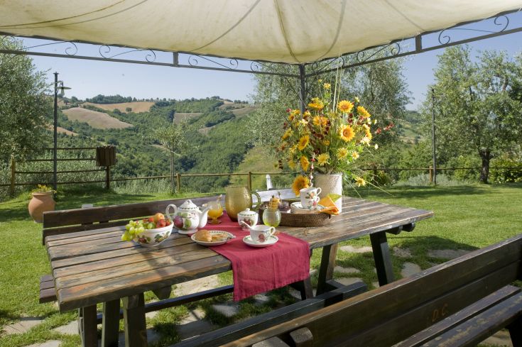 Pranzo all'aperto circondati da colline verdi e fiori variopinti, in un contesto tranquillo.