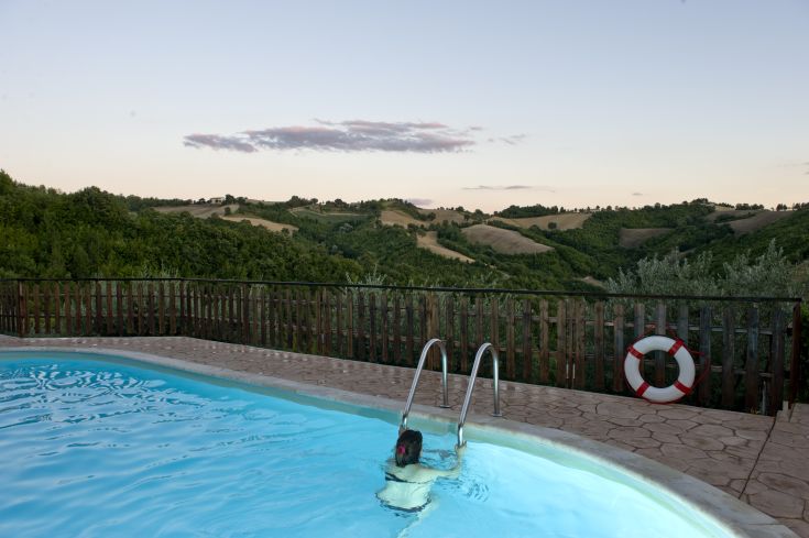 Momento di tranquillità nella piscina circondata da vegetazione tipica umbra, con viste su colline e uliveti.