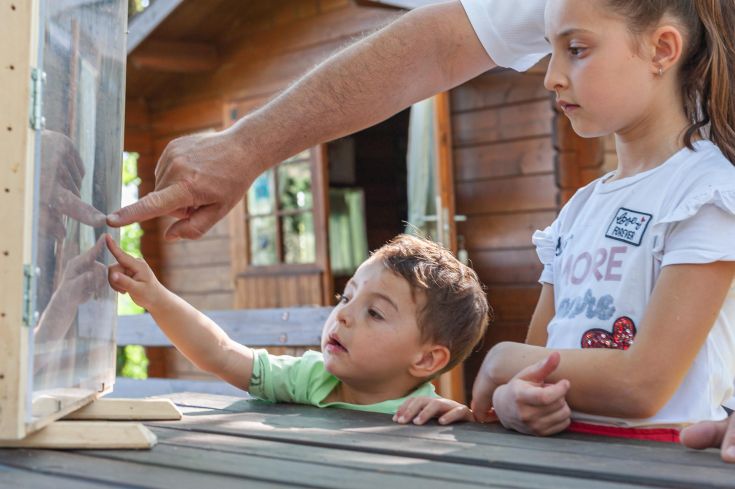 Un momento di esplorazione tra bambini e un adulto che indica un oggetto curioso.
