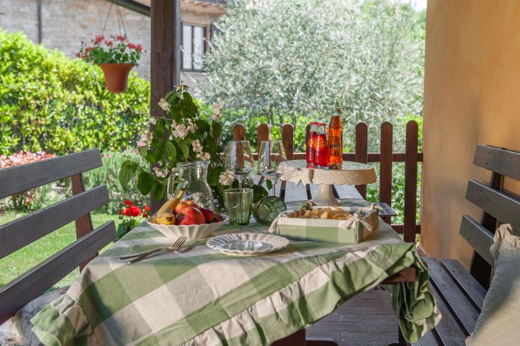Un tavolo all'aperto decorato con frutta e bevande, situato in un giardino ben curato.