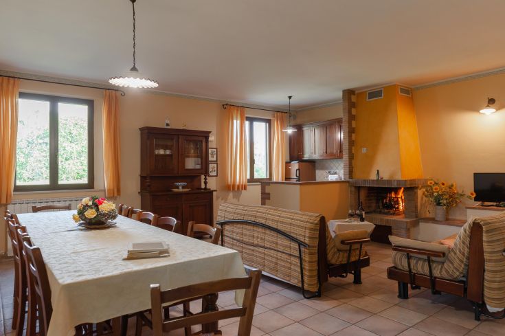 Soggiorno semplice e confortevole con camino e angolo cucina, perfetto per rilassarsi insieme alla famiglia.