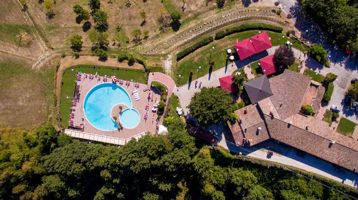 Agriturismo con piscina circondato da un ambiente naturale, perfetto per relax e immersione nella natura.