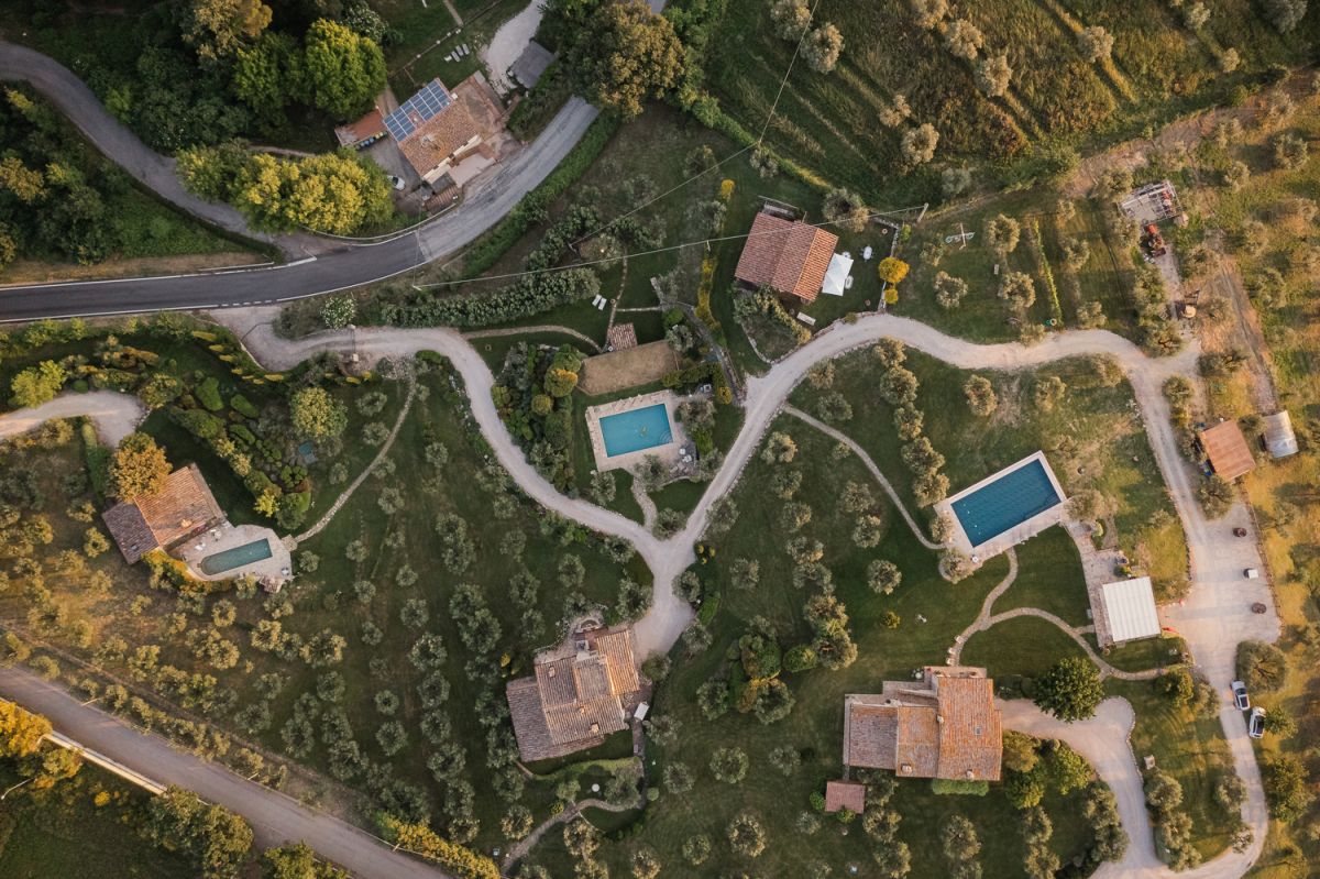 Panorama di tre edifici immersi nella natura umbra, con piscine e spazi verdi circostanti.